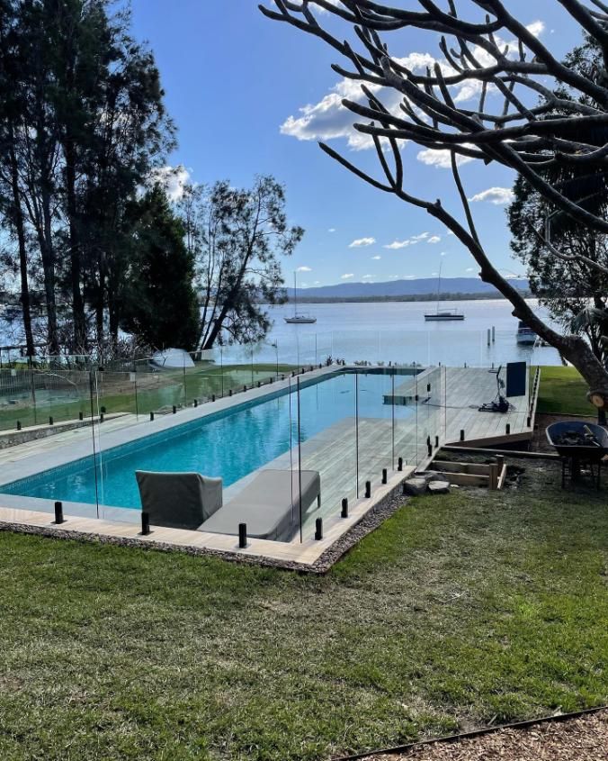 A Large Swimming Pool With a Glass Fence Around It — Reflect Glass In Tuggerah, NSW