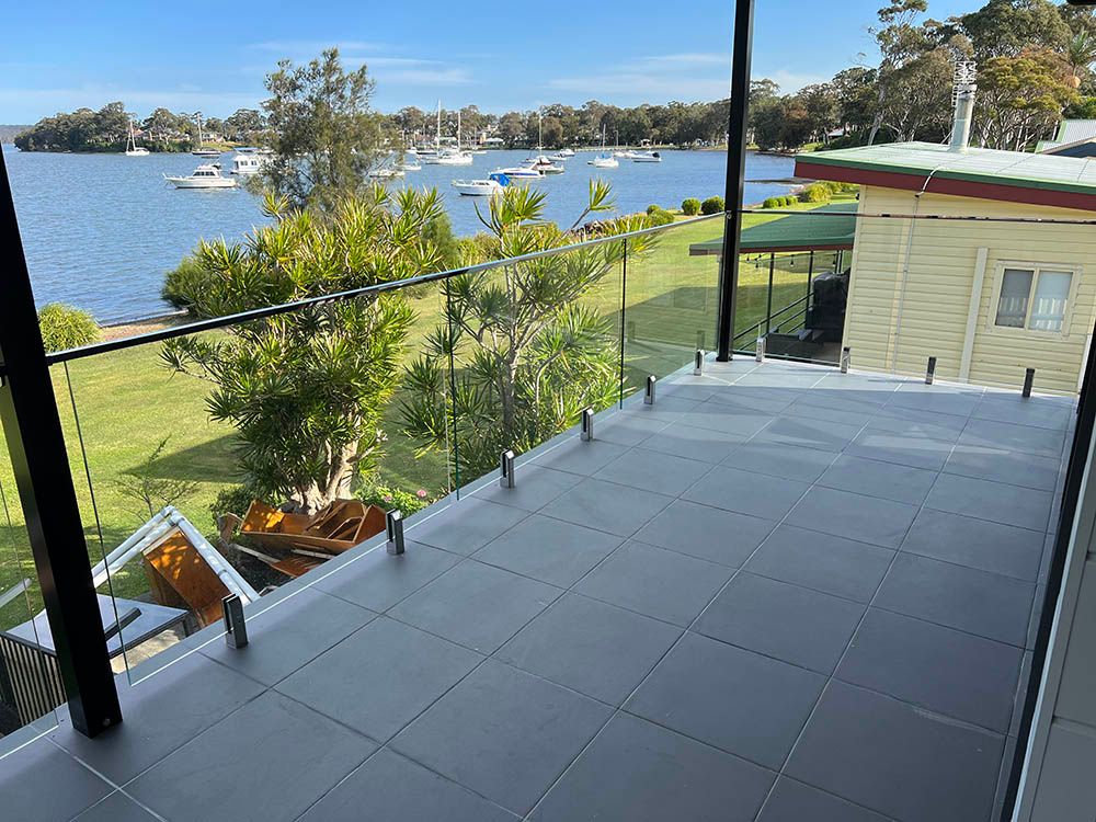 A Balcony Overlooking a Body of Water With Boats in the Water — Reflect Glass In Hunter Valley, NSW