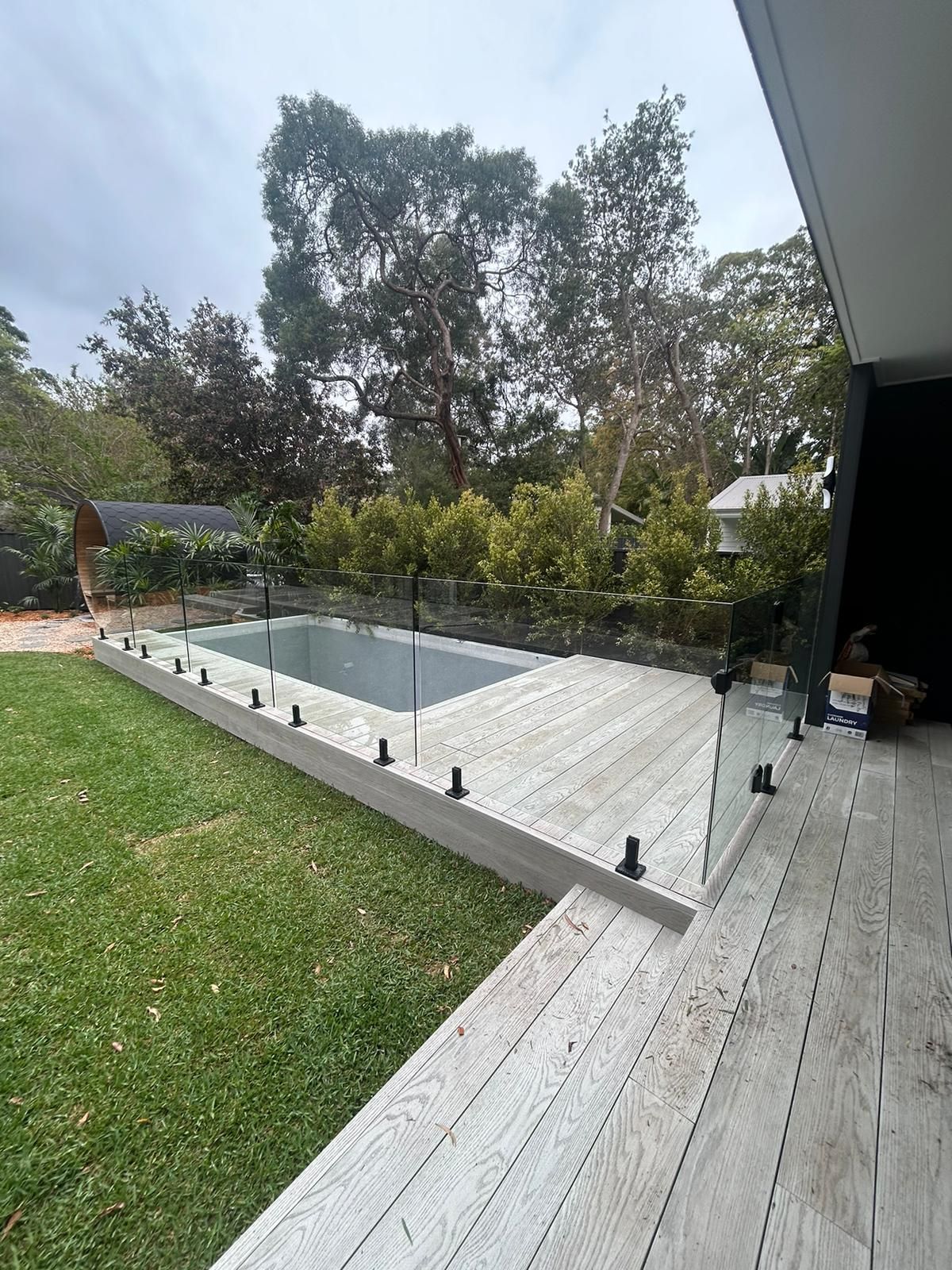 A Large Swimming Pool in the Middle of a Lush Green Yard Surrounded by Trees — Reflect Glass In Tuggerah, NSW