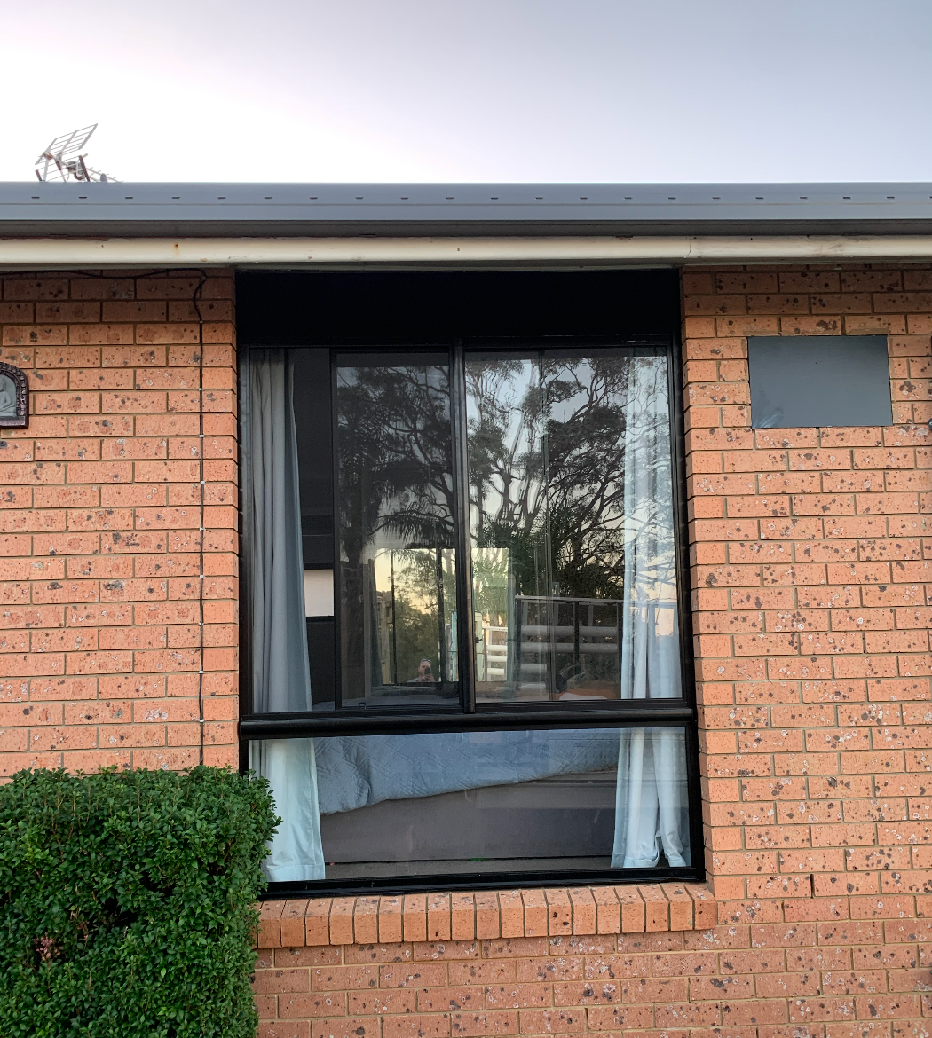 A Person Wearing Gloves is Cleaning a Window — Reflect Glass In Kincumber, NSW