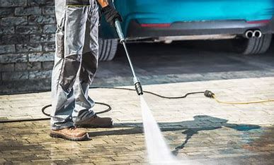 A man is using a high pressure washer to clean a driveway, You can also hire a professional to do it for you