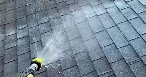 A person is spraying water on a roof with soft wash equipment. They used an Eco friendly cleaning solution.