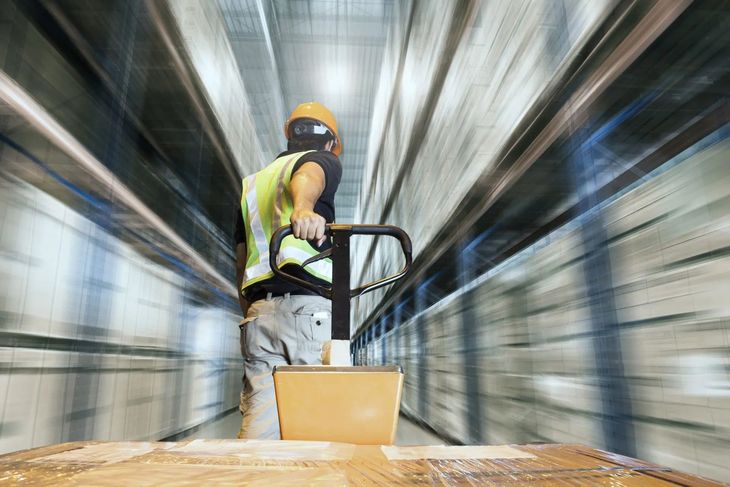 Worker in a safety vest and helmet moving a cart
