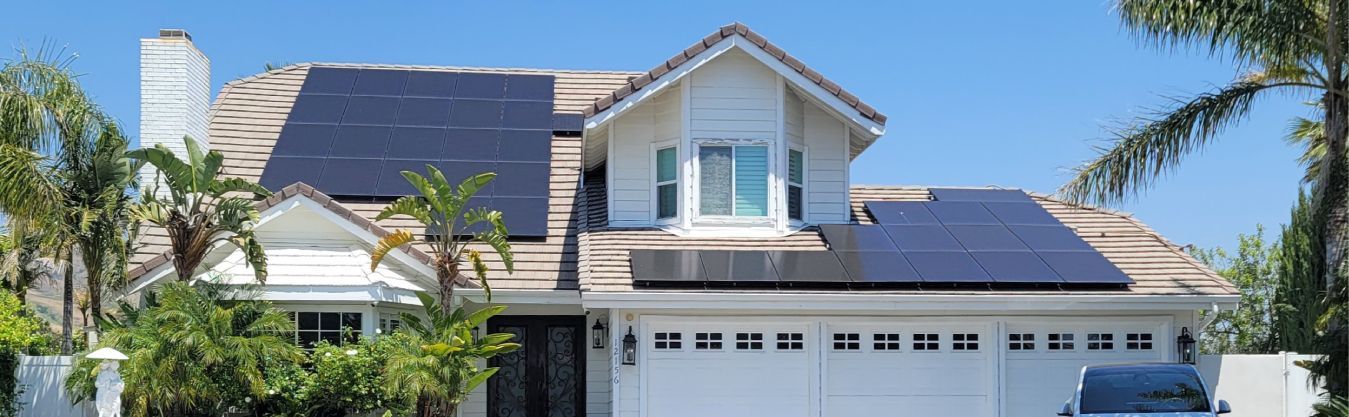 A house with solar panels on the roof and a car parked in front of it.