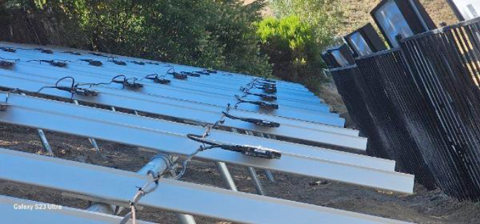 A row of solar panels sitting on top of a dirt field.