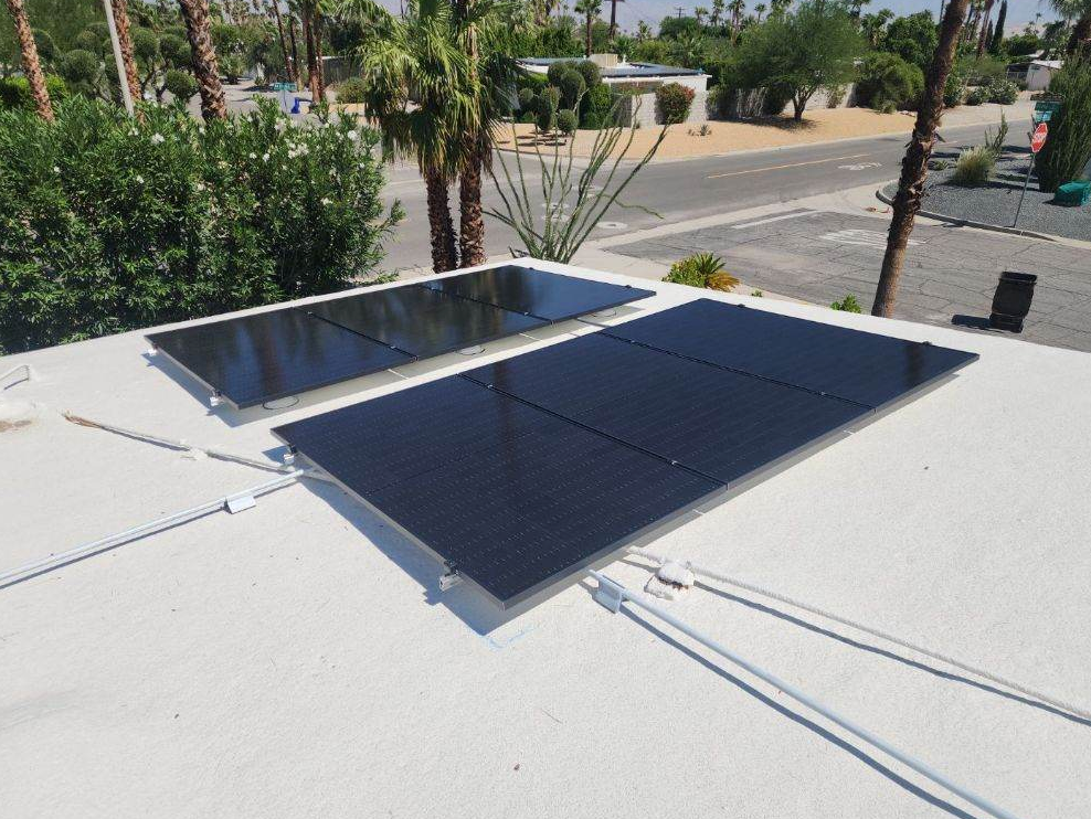 Two solar panels are sitting on top of a white roof.