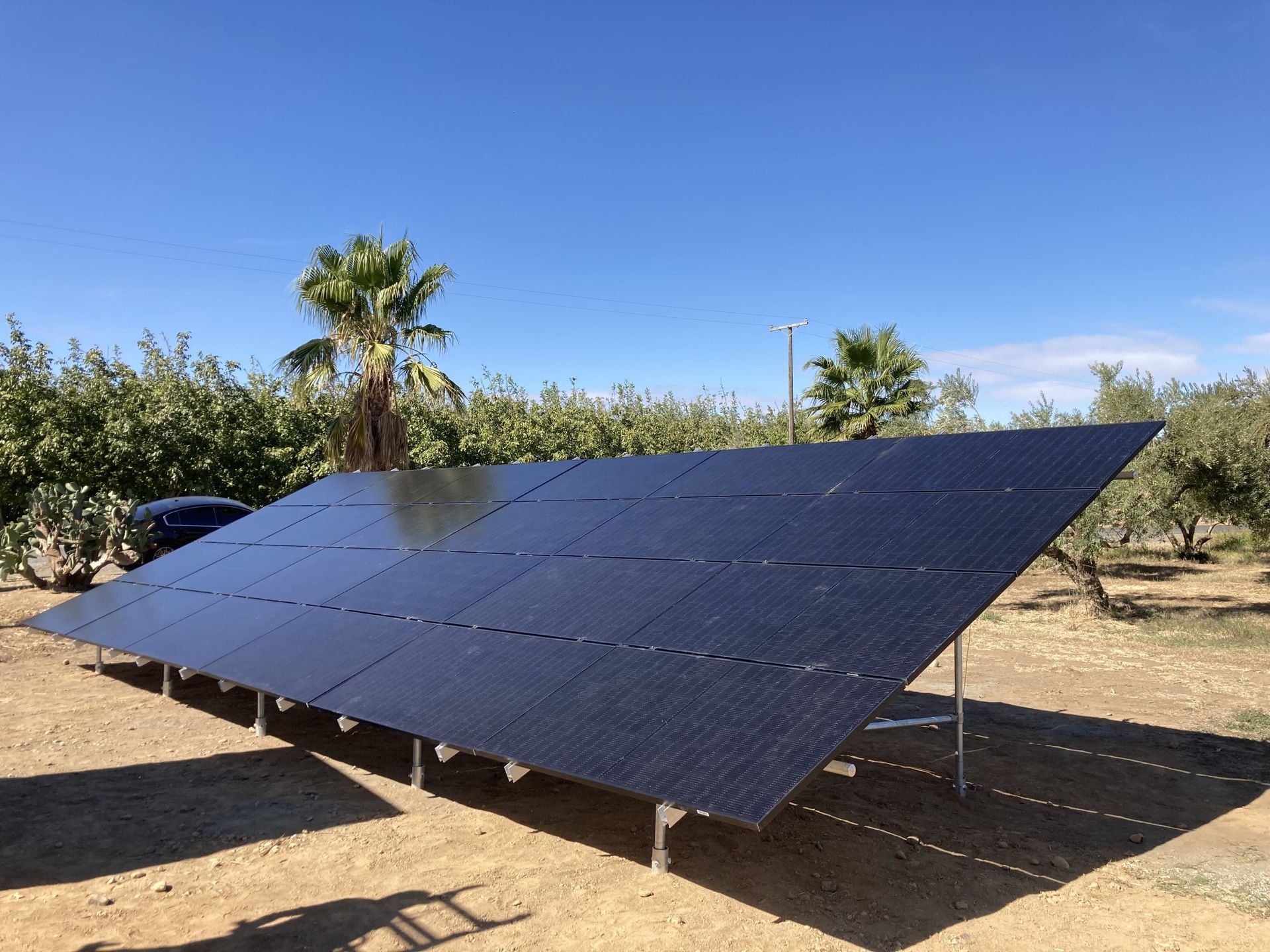 A row of solar panels are sitting on top of a dirt field.