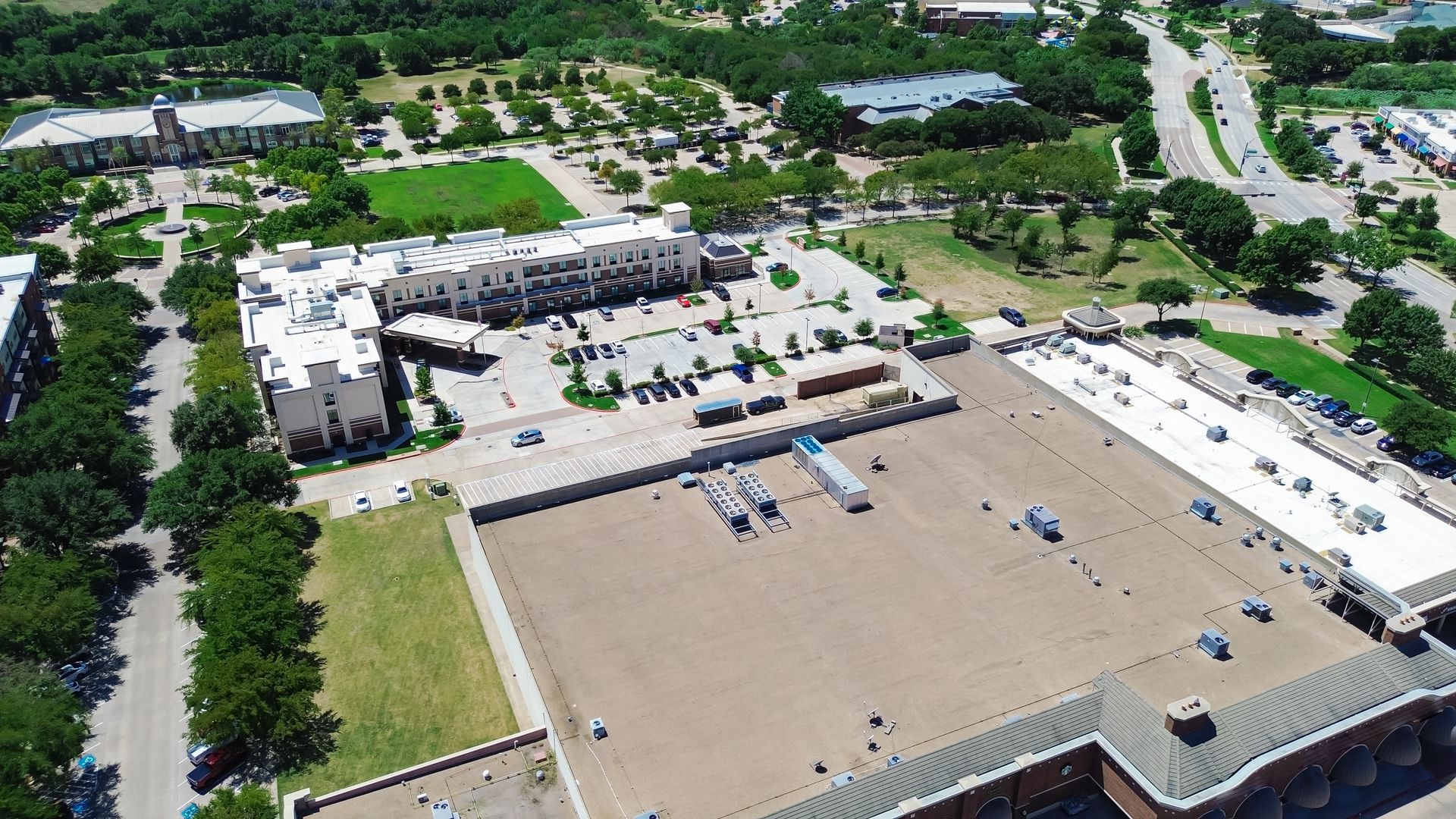 An aerial view of a large building with a lot of windows and trees in the background.