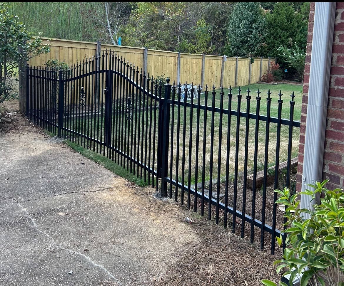 A Black Wrought Iron Fence Surrounds A Brick House