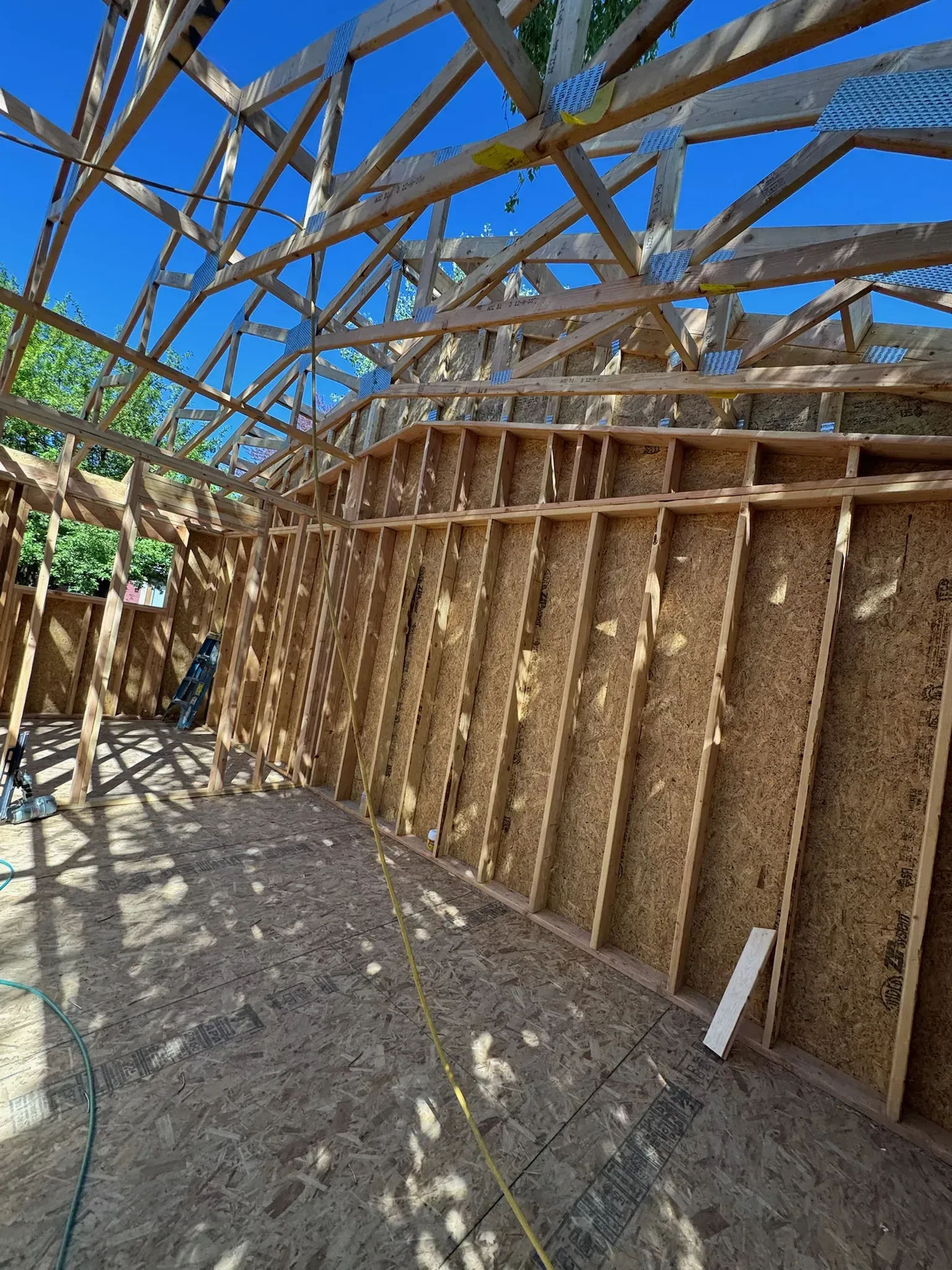 Partially built bamboo structure with woven wall panels under a blue sky