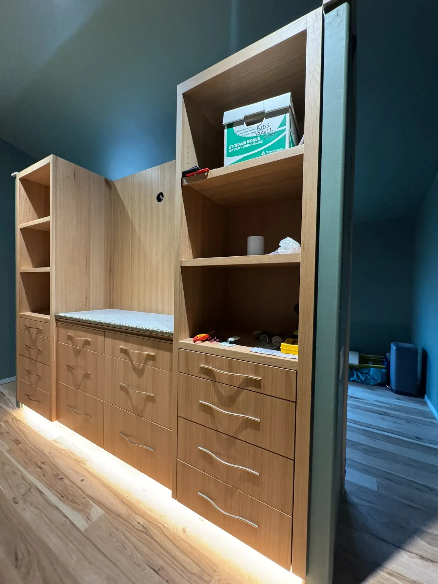 Wooden cabinets and open shelving in a modern room with warm lighting and blue walls