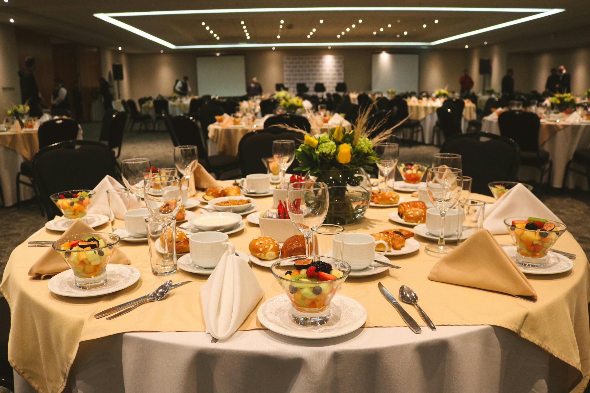 Banquet hall with round tables set for a formal dinner, white linens, and floral centerpieces