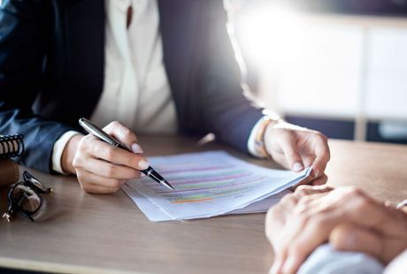 A man and a woman are sitting at a table signing a document.