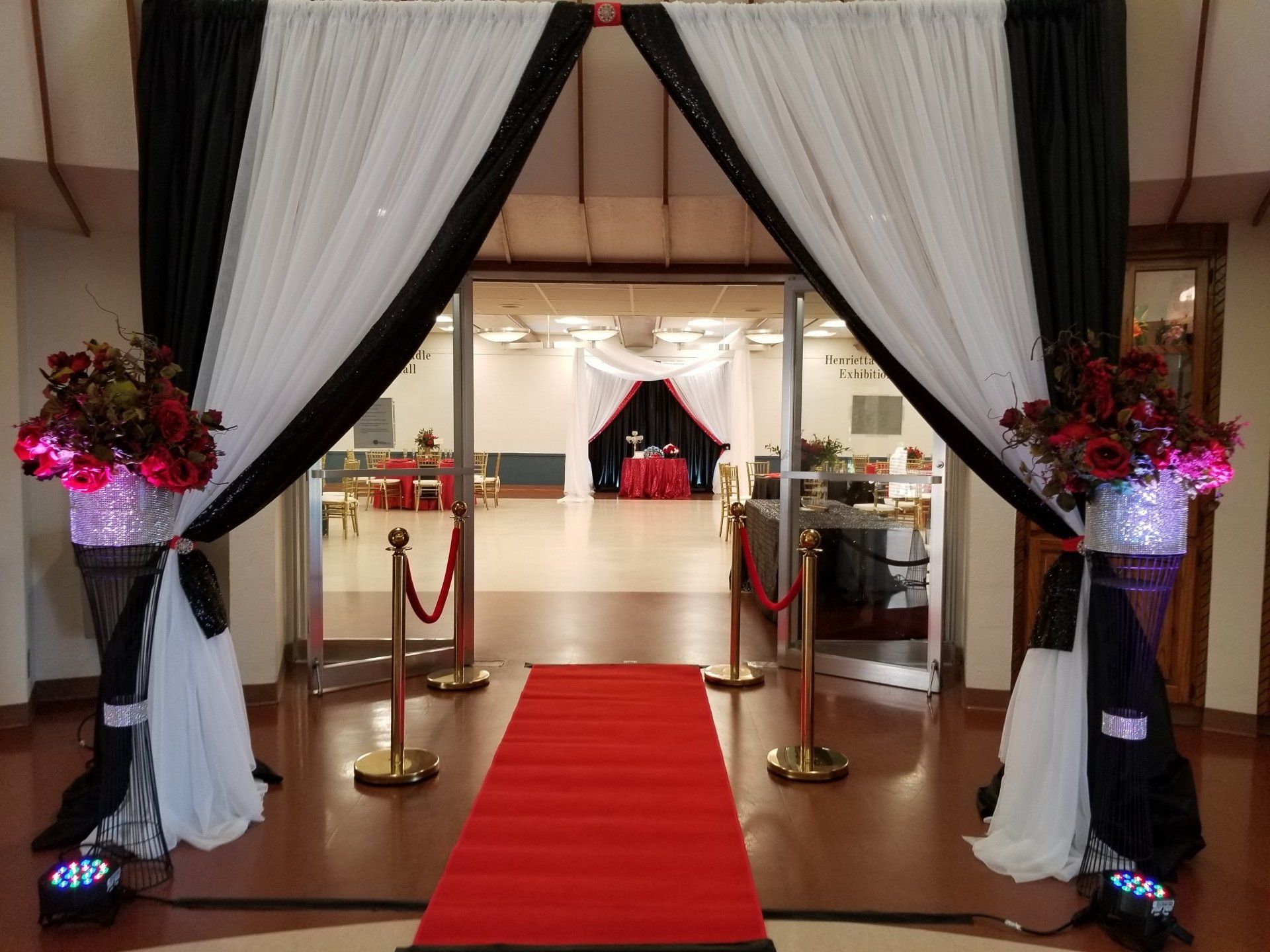 Entrance with red carpet, black and white draped doorway, floral arrangements.