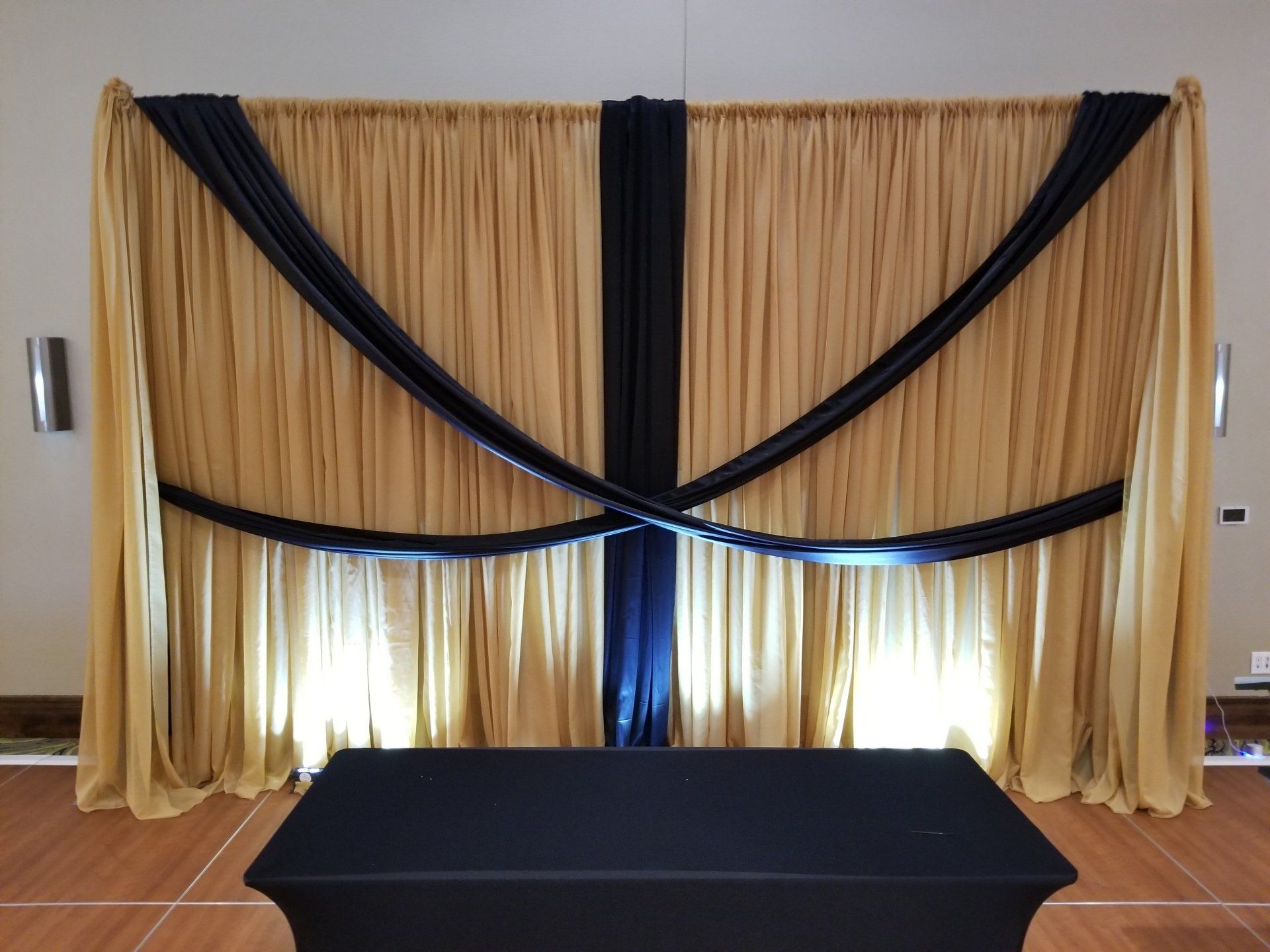 Gold and black draped backdrop with a black table in front.