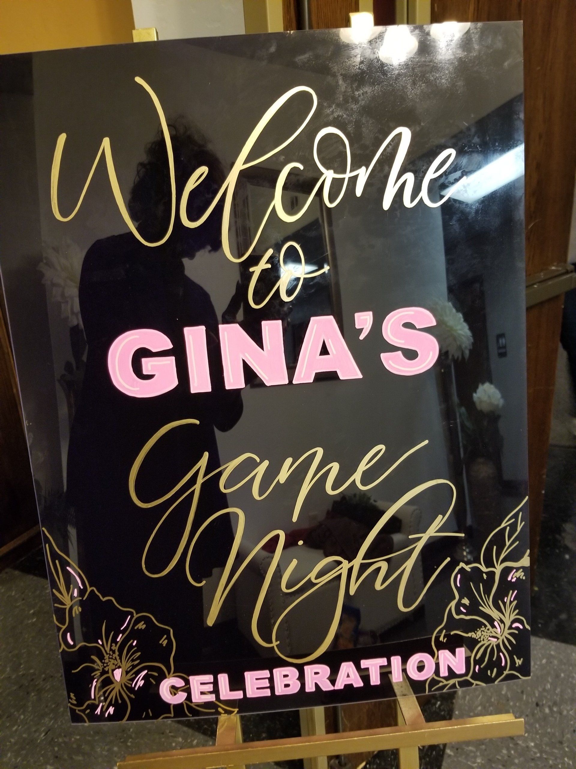 Black sign with gold and pink text: