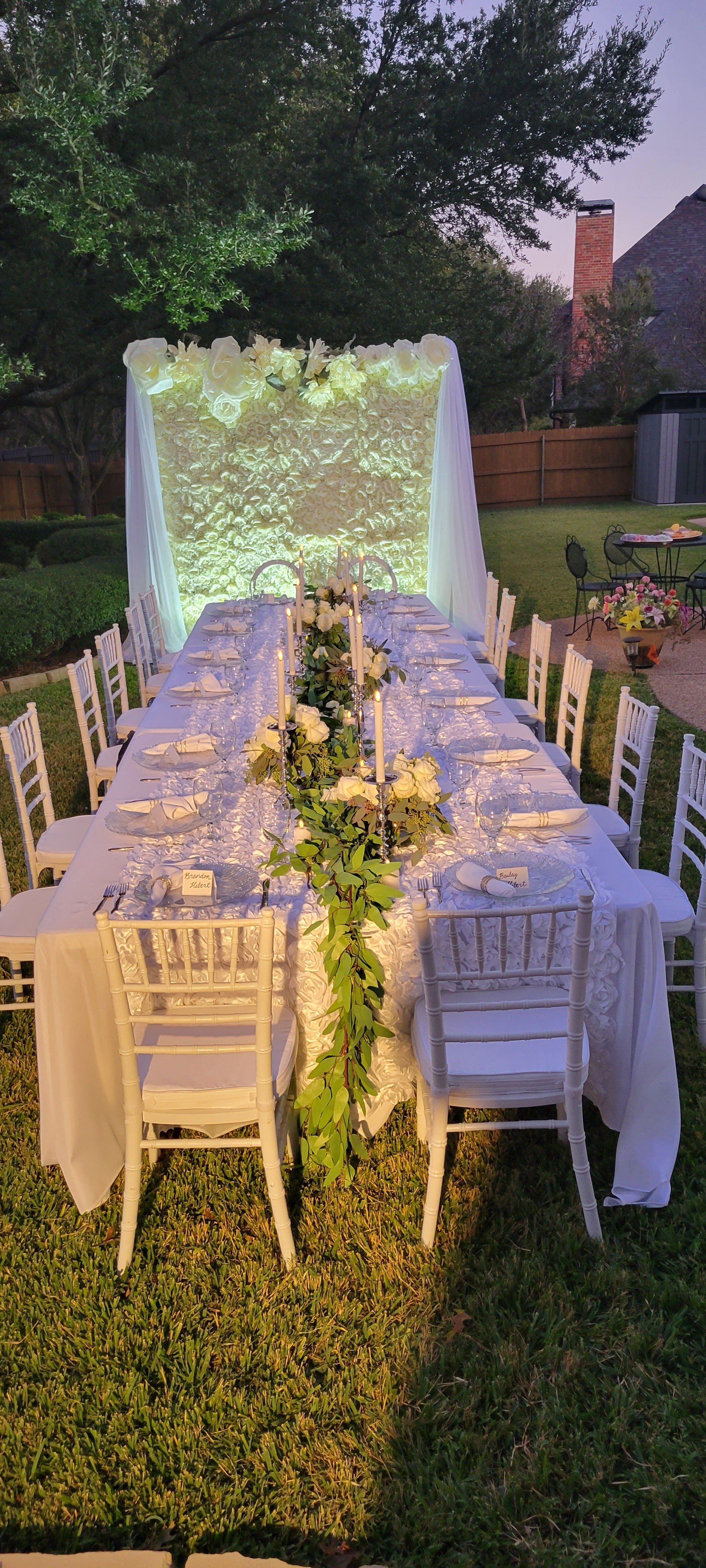 Outdoor dining table set for a special event with white flowers and decorations.