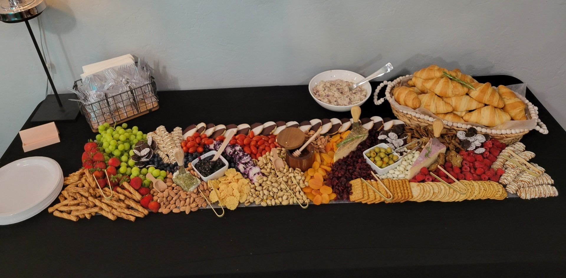 A large charcuterie board with various snacks, including fruit, crackers, and olives.