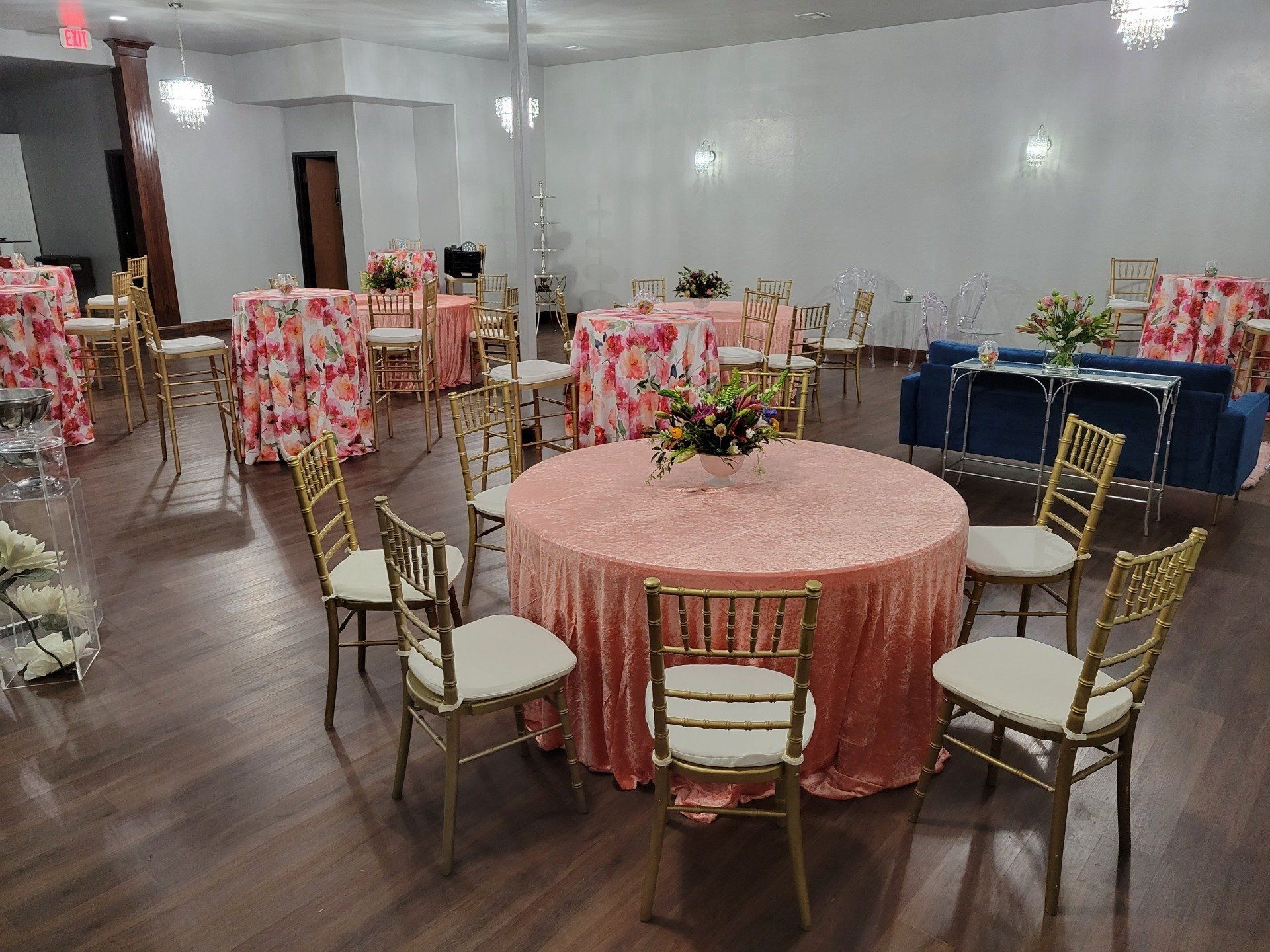Event hall with round tables, chairs, and colorful tablecloths set for a gathering.