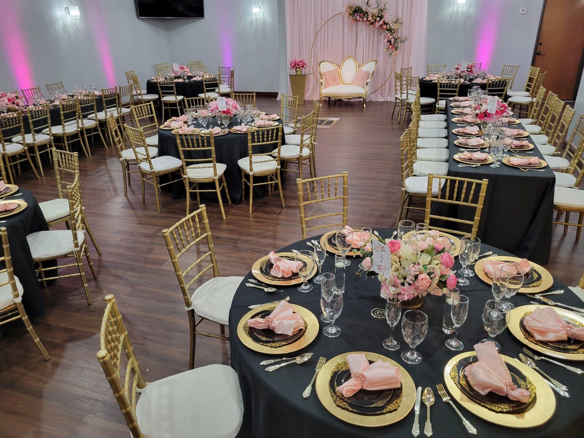 Event space set up with tables, gold chairs, pink and black decor.