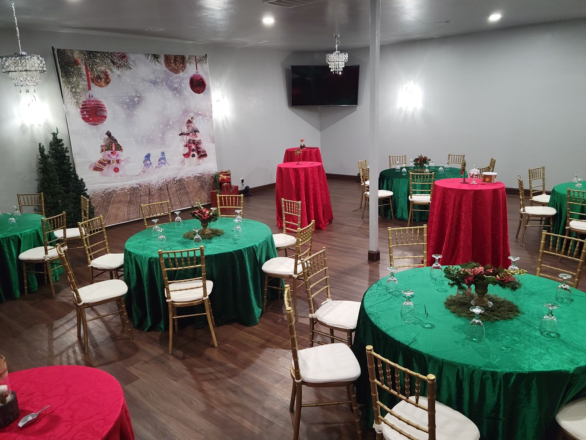 Christmas party venue with red and green tablecloths, gold chairs, and festive decorations.