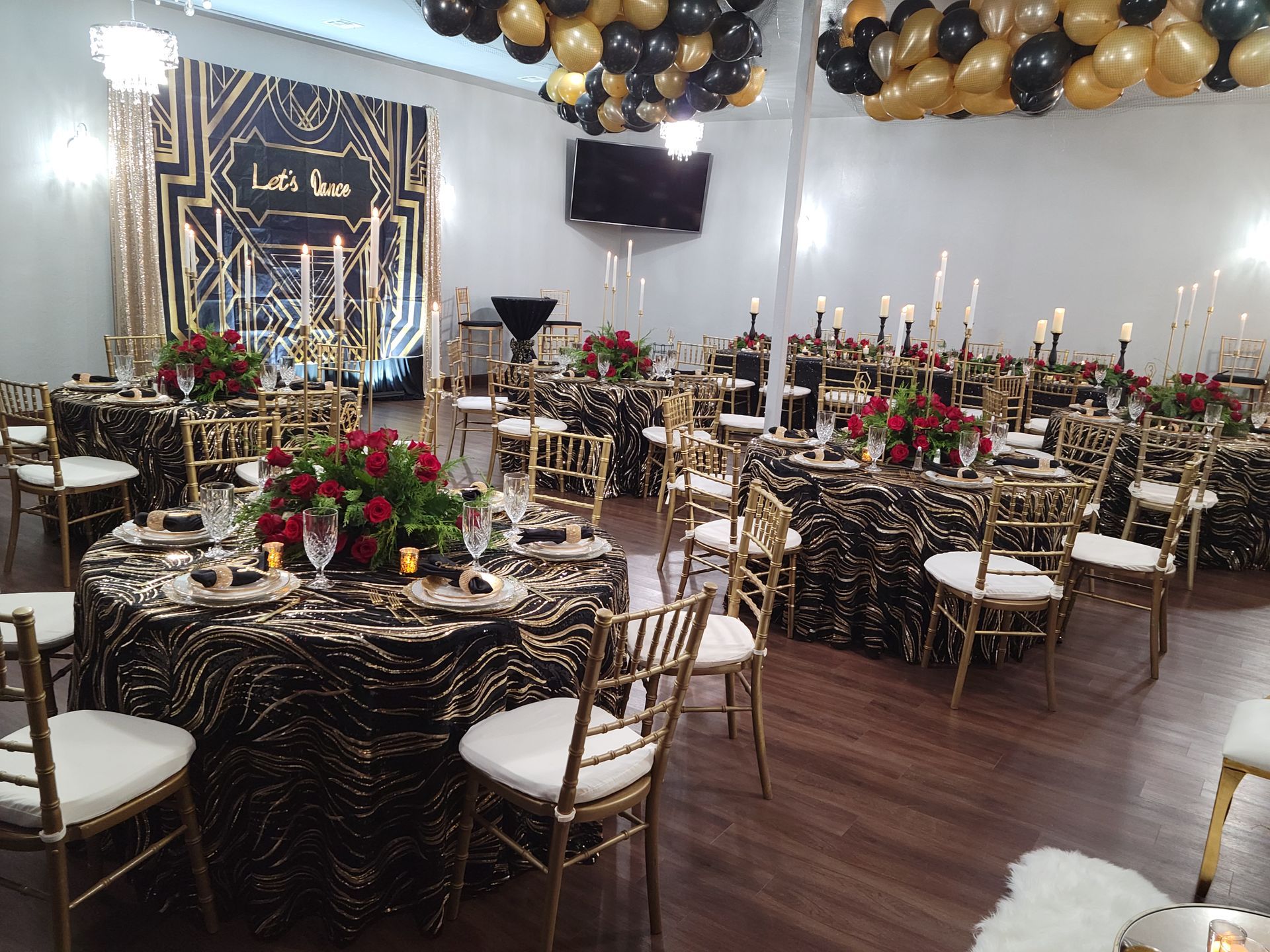 Elegant event space with round tables, gold chairs, and black & gold decor.