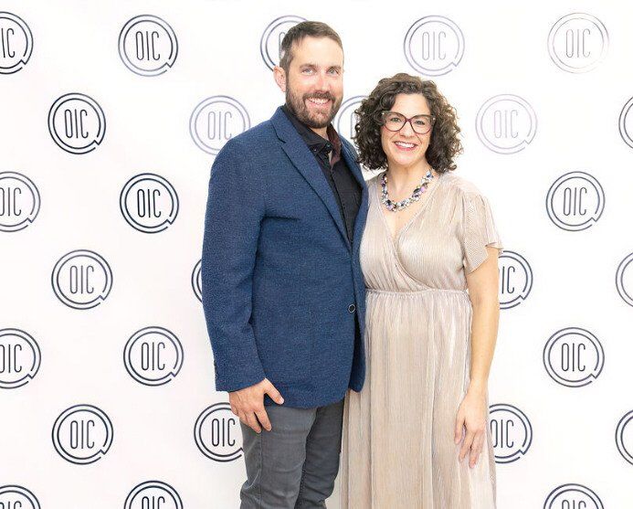 Couple posing in front of a backdrop with repeated 
