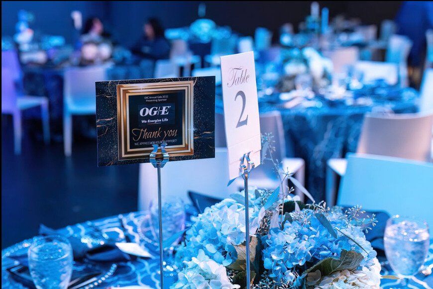 Table setting at a formal event, featuring blue floral arrangements, table number, and thank you card.