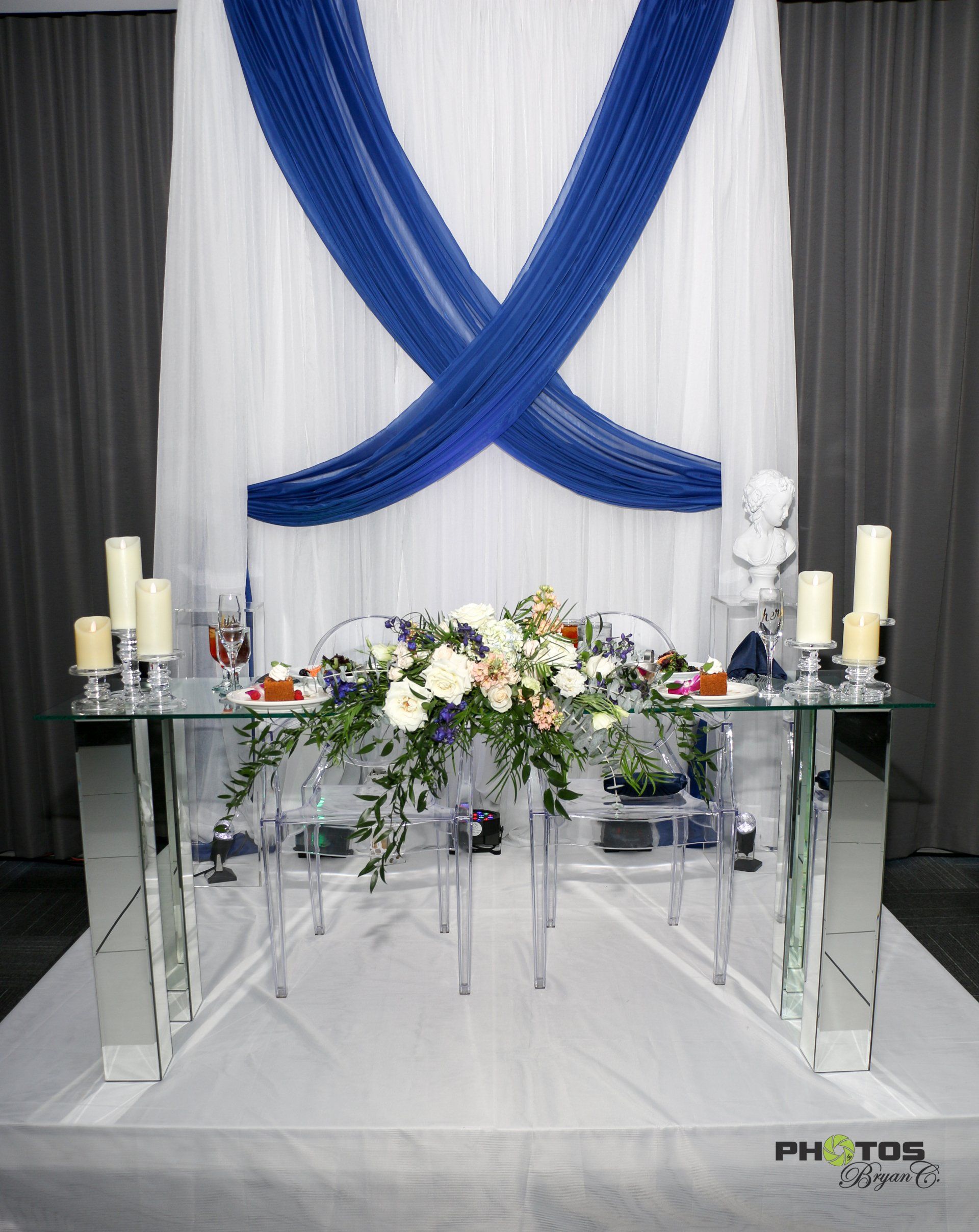 Wedding reception table with blue and white decor, floral arrangement, and candles.