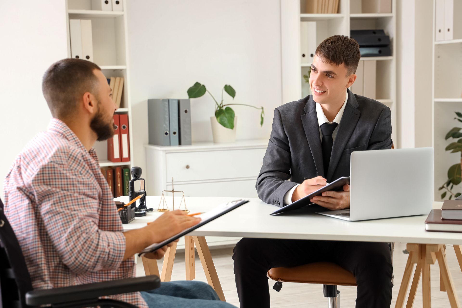 A young personal injury attorney meets with a client in a wheelchair.