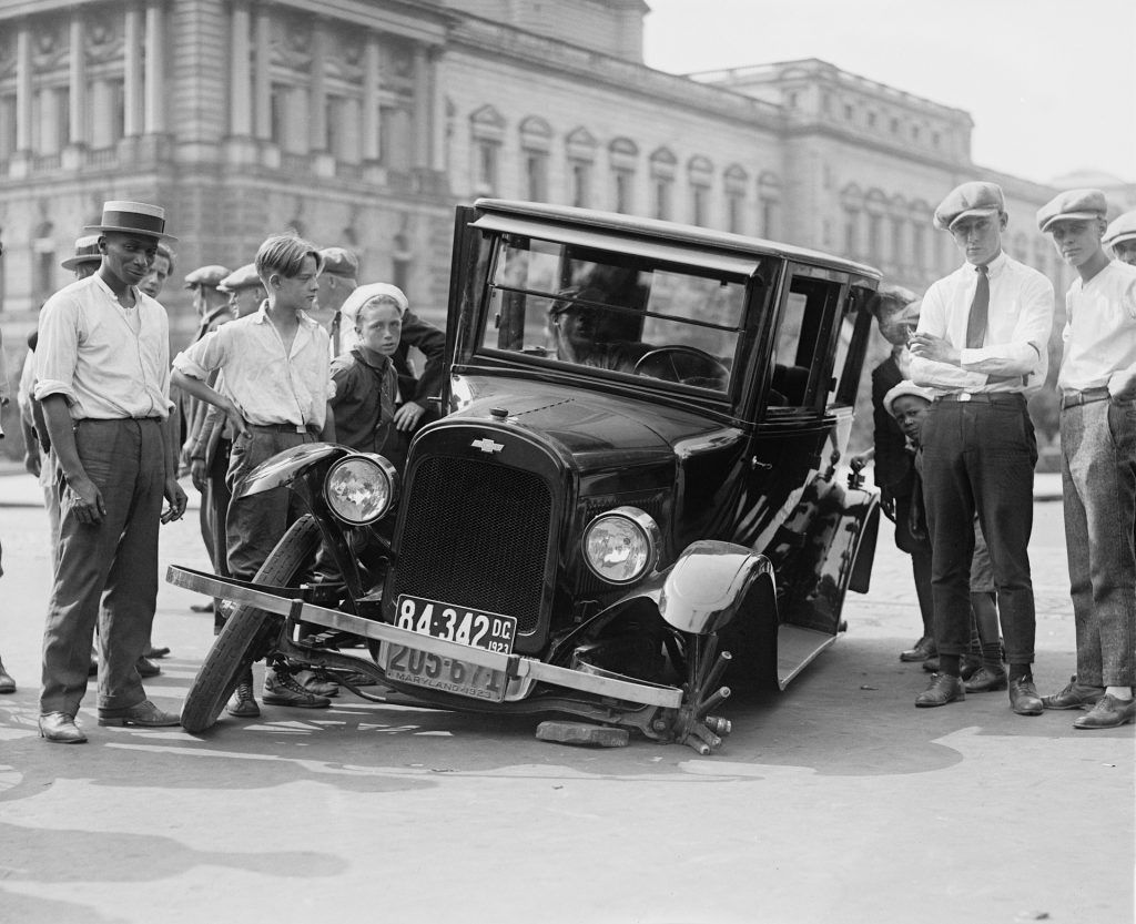 A group of men are standing around a damaged car.