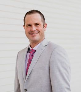 A man in a suit and tie is smiling for the camera.