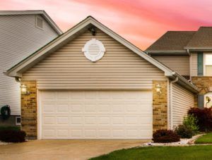 A house with a white garage door and a pink sky in the background.