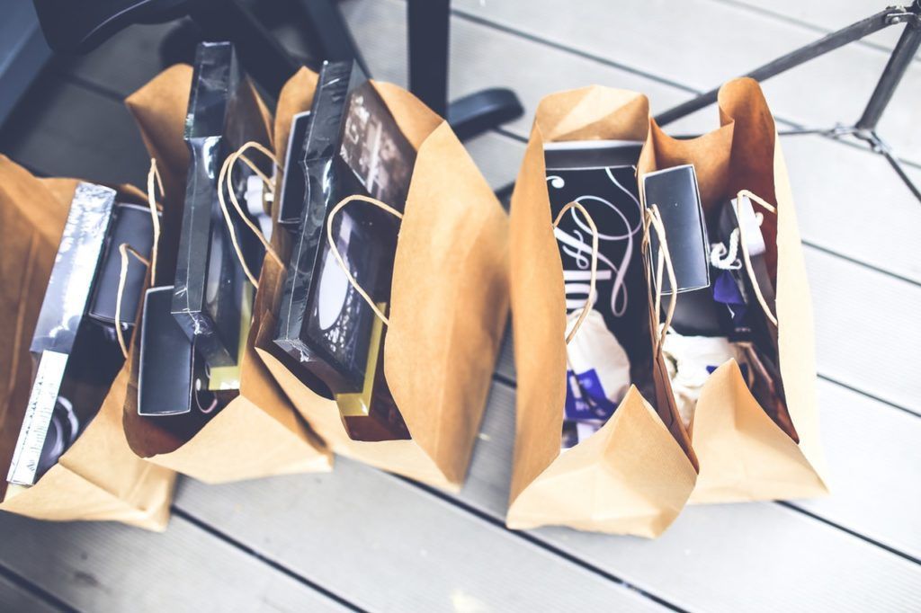 A row of brown bags filled with electronics on a wooden floor.