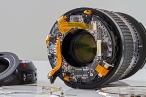A camera lens is being disassembled on a table.