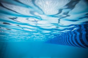 Looking up at a swimming pool from underneath the water.