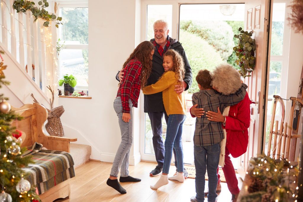A family is hugging each other in a living room at christmas.