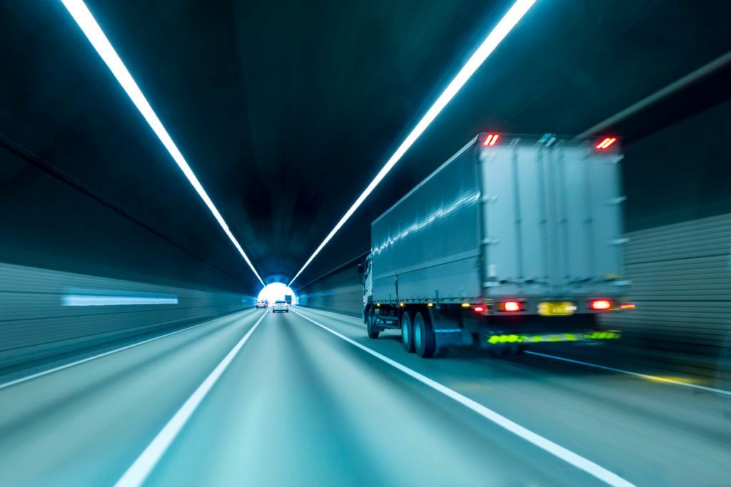 A truck is driving through a tunnel on a highway.