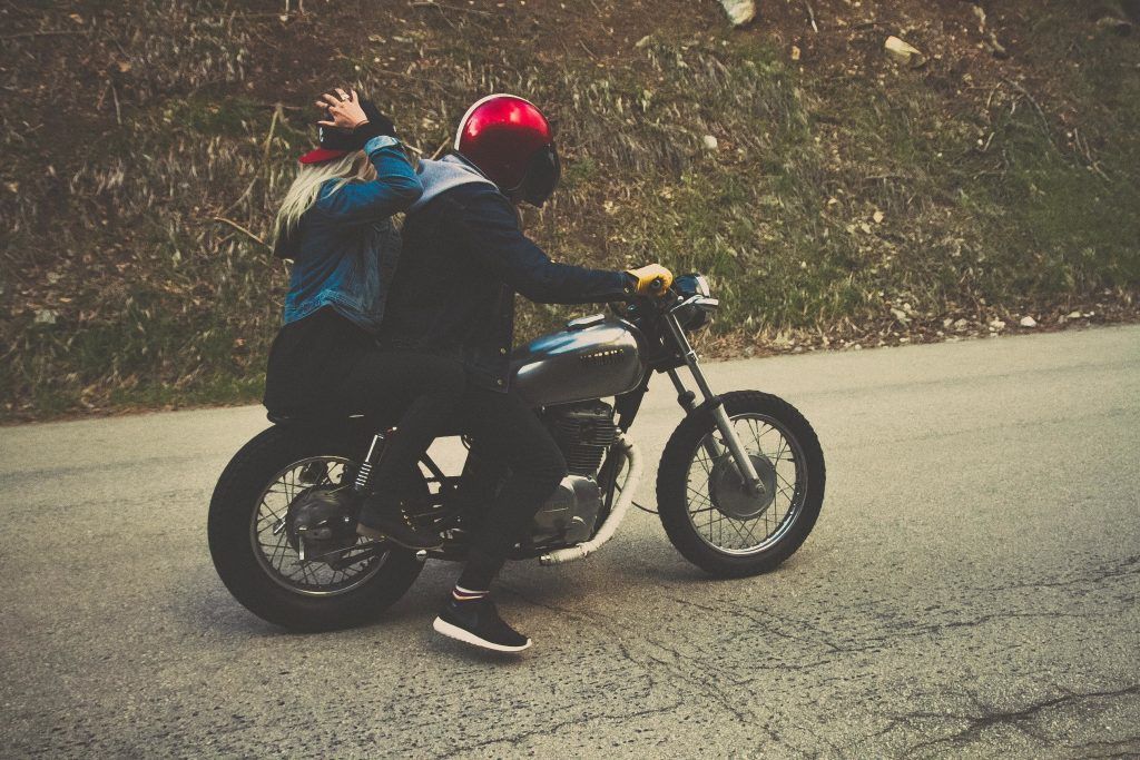 A man and a woman are riding a motorcycle down a road.