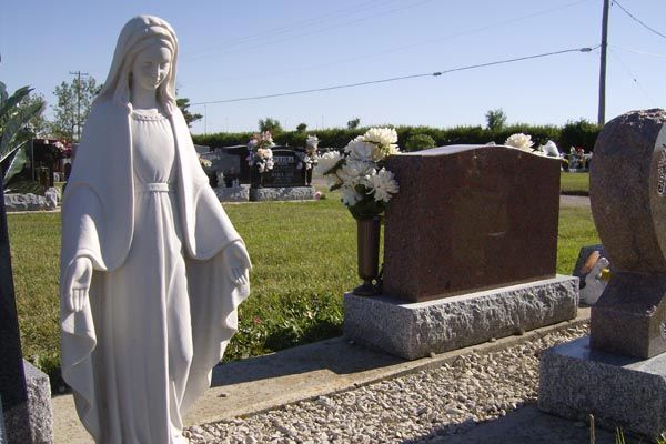 A statue of a woman standing in front of a grave