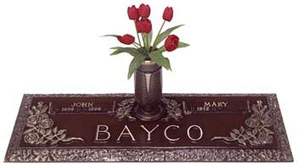 A gravestone with a vase of flowers on top of it.