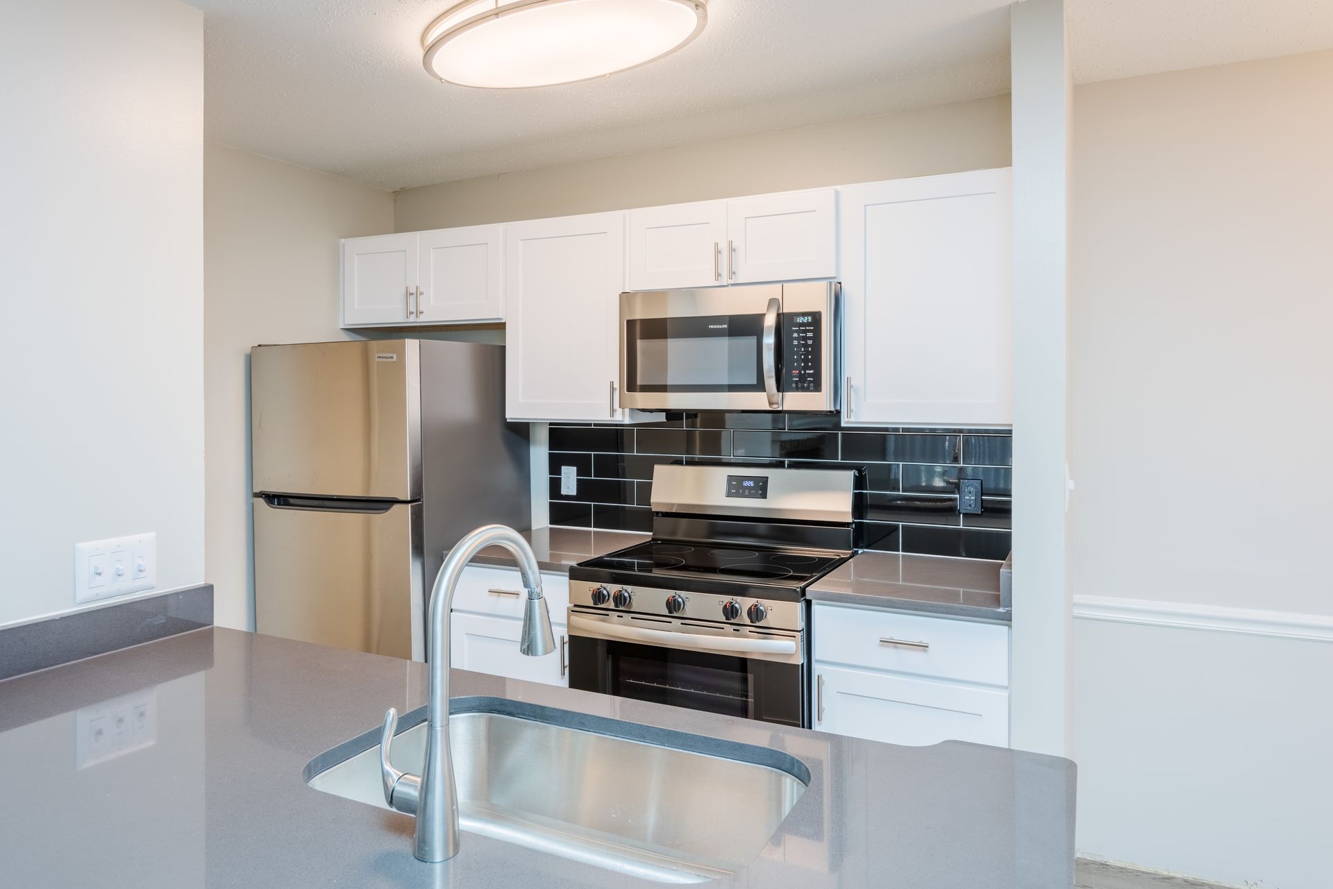 Modern kitchen with stainless steel appliances, white cabinets, and gray countertops. Contact us today to take a tour of our 1, 2, and 3-bedroom apartments for rent in Charlotte, NC.