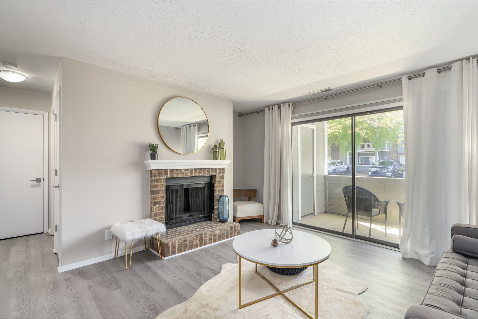 Cozy living room with fireplace, round mirror, marble coffee table, and balcony access. Contact us today to take a tour of our 1, 2, and 3-bedroom apartments for rent in Charlotte, NC.