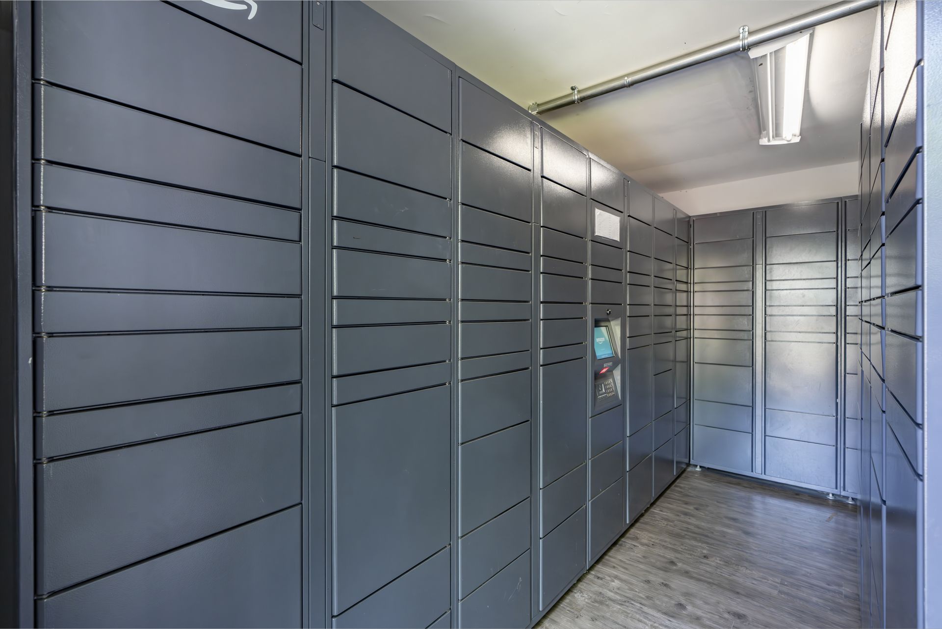 Row of gray parcel lockers in a hallway, with a tiled floor and overhead lighting. Our apartments in Charlotte, NC offer a convenient location and top-notch amenities. Call today to schedule your tour!