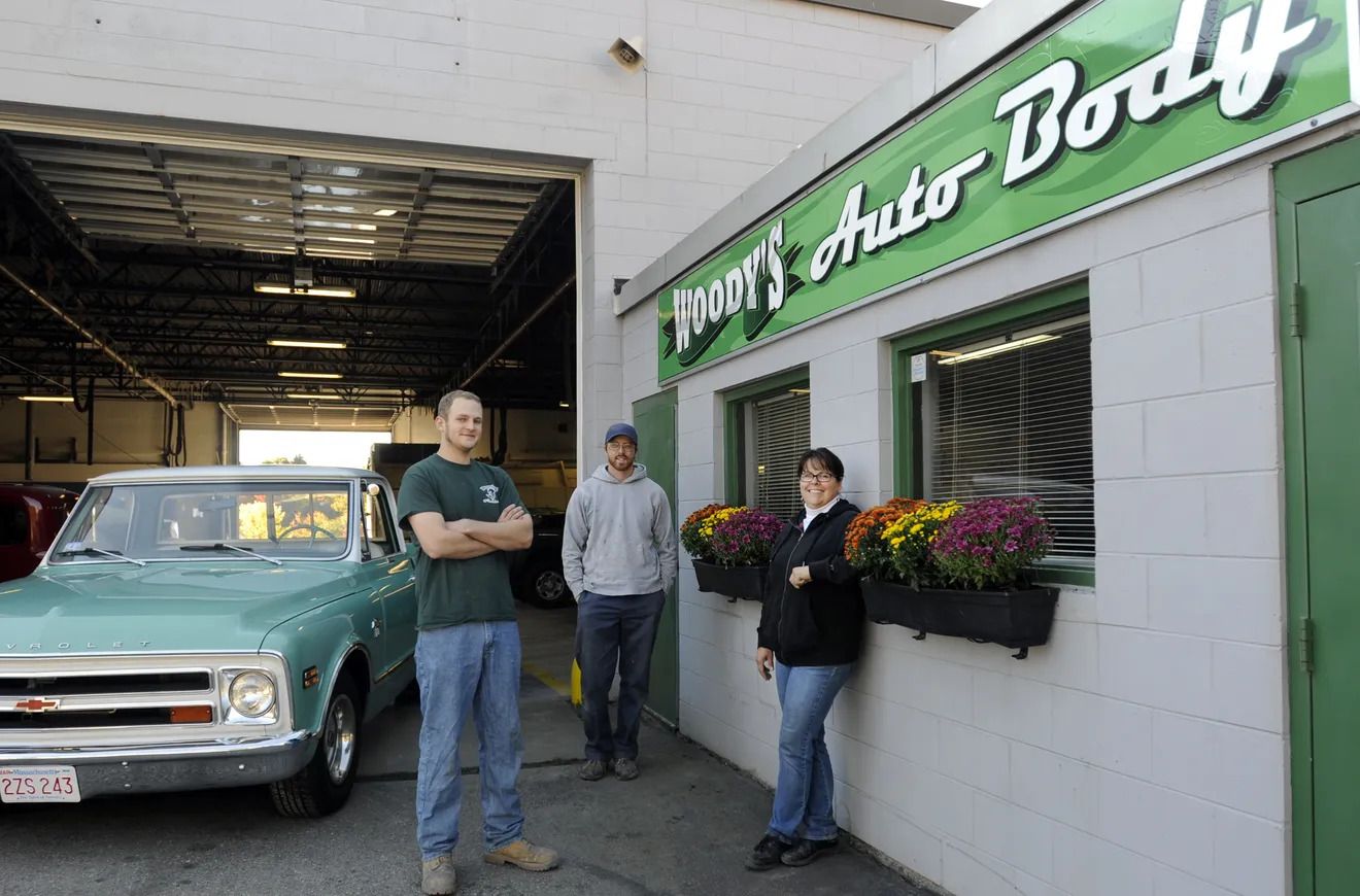 A group of people standing outside of a body shop