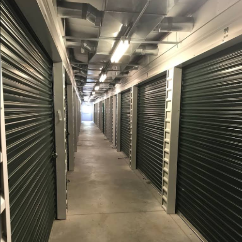 Rows of filing cabinets in a library storage area. Narrow aisle with long overhead light.