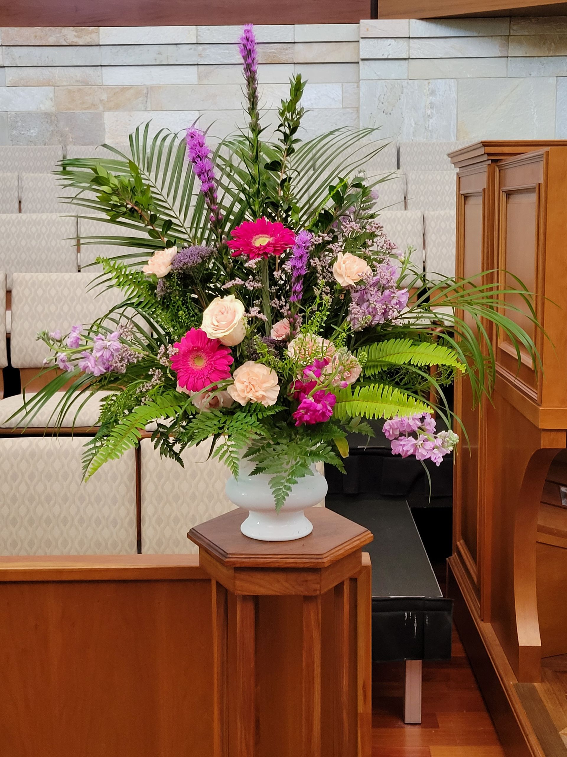 A vibrant floral arrangement with pink and purple flowers on a church altar.