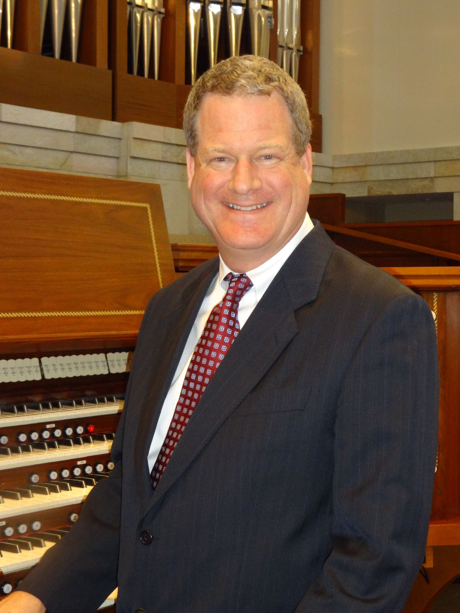 Dr. Brice Gerlach smiling while seated at the church pipe organ.