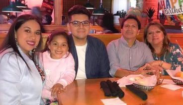 A joyful family photo of Eduardo Martinez seated with his family.