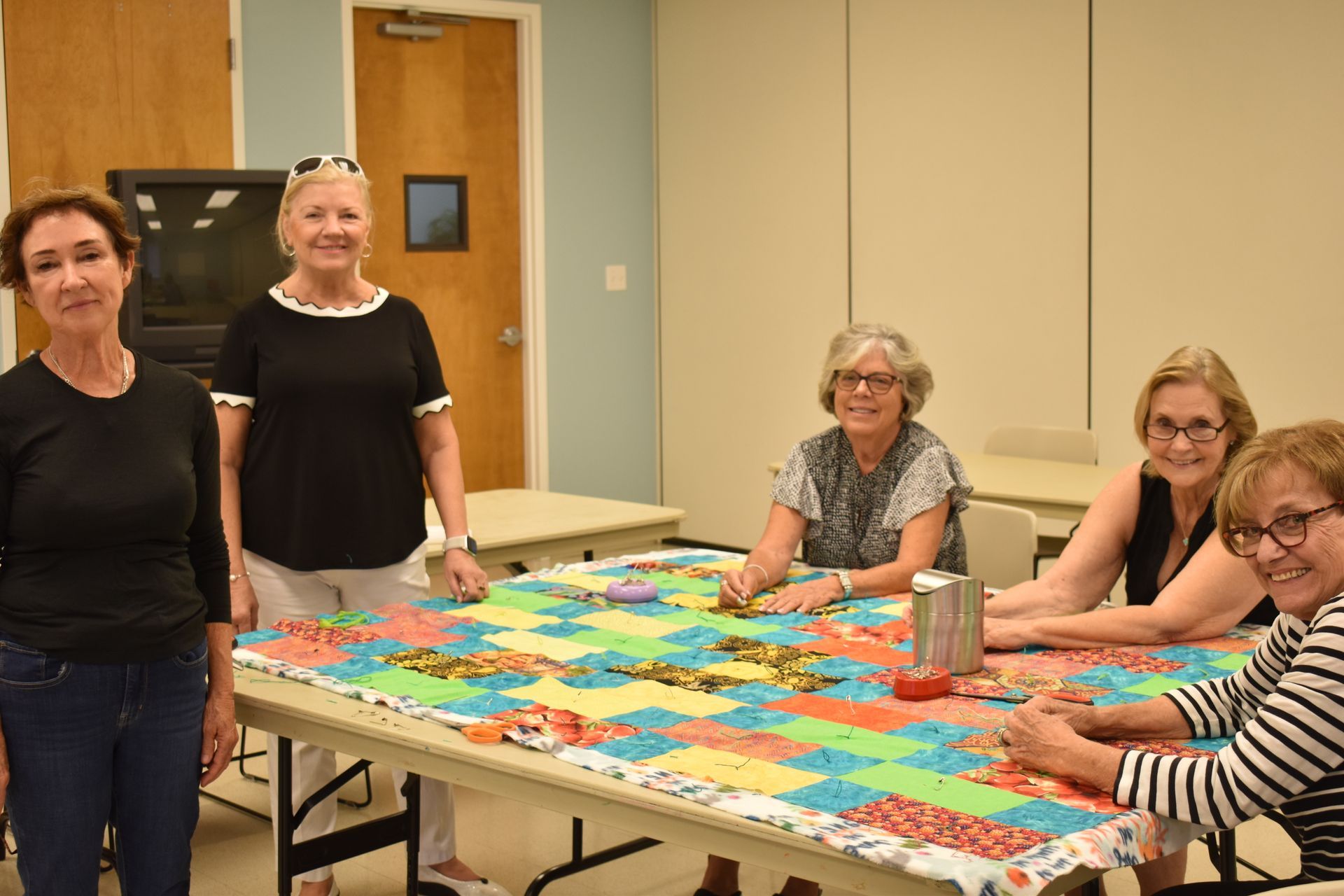 Dedicated members of the Helping Hands Quilters group collaborating together on a fabric quilting project.
